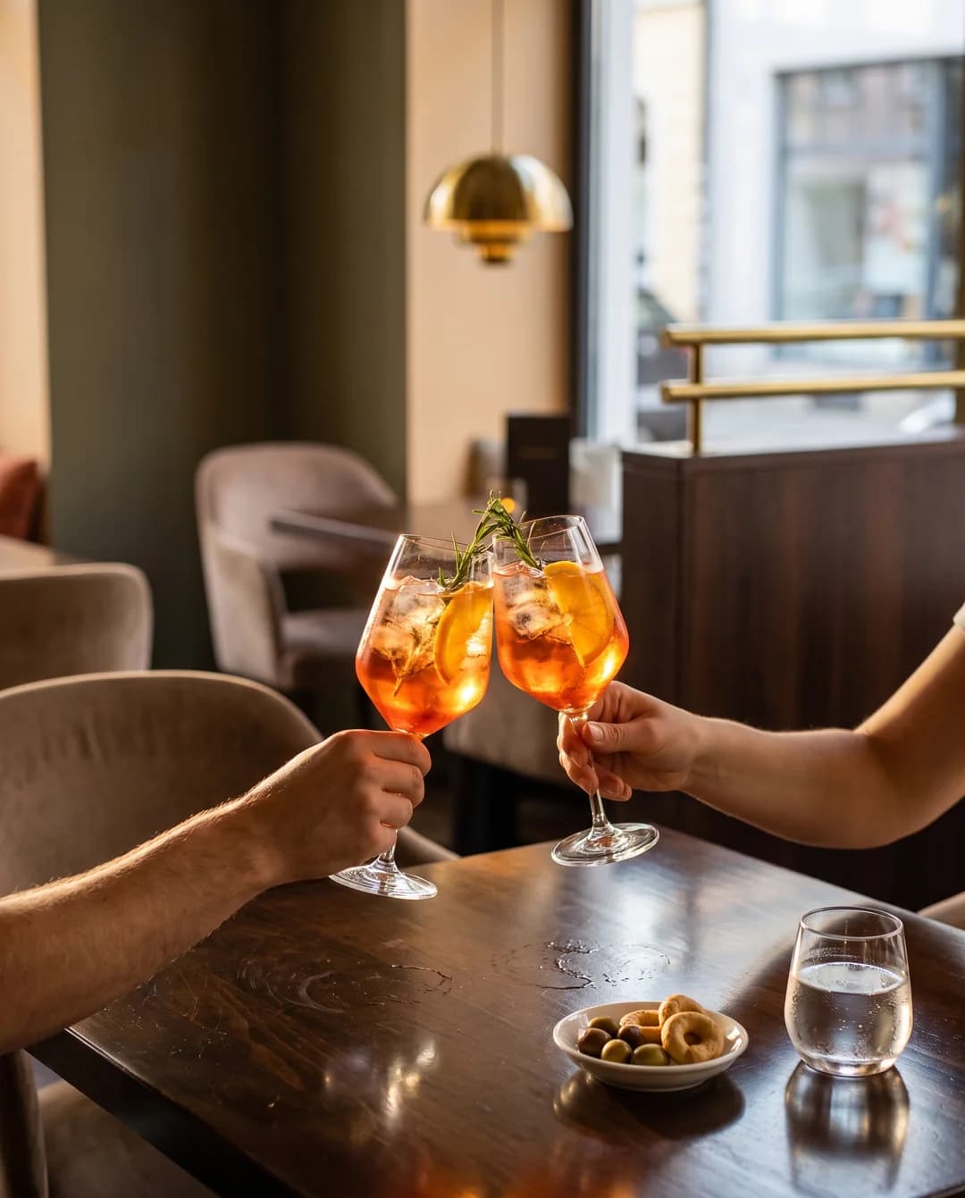 Zwei Gläser Aperitivo stoßen an einem Restauranttisch an